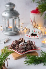 Healthy sweets, homemade candy balls with oatmeal and cocoa, sprinkled with crushed almonds in Christmas style on a star-shaped plate on a light background. Scandinavian cuisine.