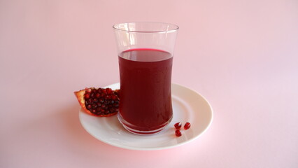 Glass of fresh pomegranate juice on green background