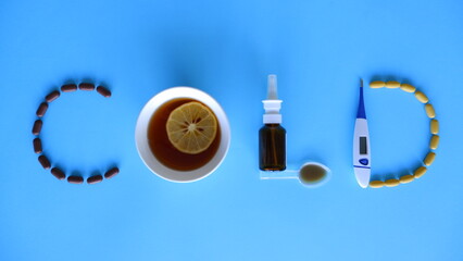 Cold word laid out of medications, pills, thermometer, traditional medicine for treating colds, flu, heat on a blue background. Maintenance of immunity. Seasonal diseases. Top view. Medicine flat lay
