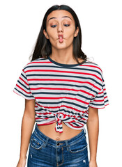 Fototapeta premium Young hispanic girl wearing casual clothes making fish face with lips, crazy and comical gesture. funny expression.