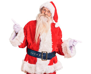Old senior man with grey hair and long beard wearing traditional santa claus costume smiling confident pointing with fingers to different directions. copy space for advertisement