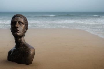 Fototapeta na wymiar ancient bronze head statue on the beach