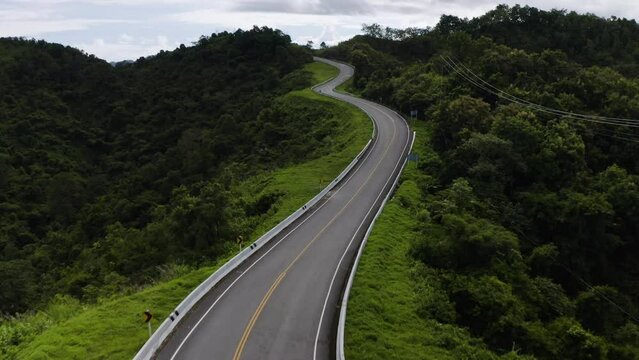 Aerial footage of a winding road in the rainy season on a tropical rainforest mountain in Nan province, Thailand
