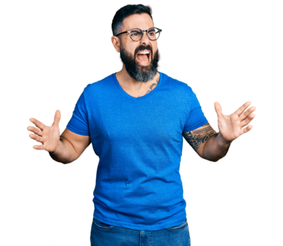 Hispanic man with beard wearing casual t shirt and glasses crazy and mad shouting and yelling with aggressive expression and arms raised. frustration concept.