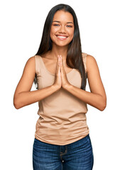 Beautiful hispanic woman wearing casual clothes praying with hands together asking for forgiveness smiling confident.