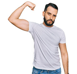 Young man with beard wearing casual white t shirt strong person showing arm muscle, confident and proud of power