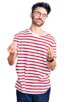 Young hispanic man wearing casual clothes doing money gesture with hands, asking for salary payment, millionaire business