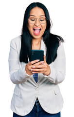 Beautiful hispanic woman with nose piercing using smartphone typing message celebrating crazy and amazed for success with open eyes screaming excited.