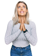 Beautiful blonde woman wearing casual clothes begging and praying with hands together with hope expression on face very emotional and worried. begging.