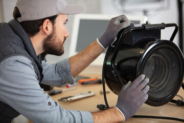 repairman working on portable fan in the workshop