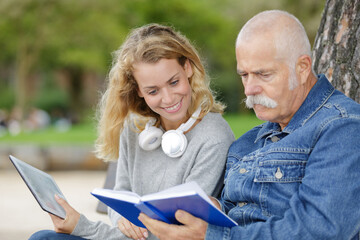 senior man woman and daughter reading outside