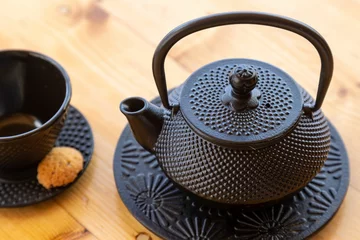 Keuken foto achterwand Top view of a cast iron teapot and a tea cup, mug set on a wooden table © Damián Méndez/Wirestock Creators