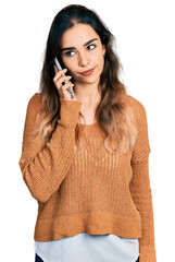 Beautiful hispanic woman having conversation talking on the smartphone thinking attitude and sober...