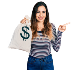 Beautiful hispanic woman holding dollars bag smiling happy pointing with hand and finger to the side