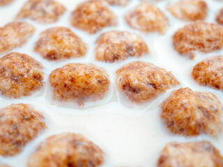Selective focus on swollen corn balls in milk close up. A quick delicious breakfast of corn flakes and milk.
