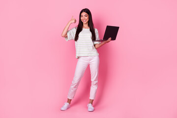 Full body portrait of cheerful attractive malaysian lady demonstrate thumb up hold laptop isolated on pink color background