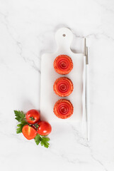 Tomato mousse cream appetizer of round cylindrical shape with tourbillon jelly, on a serving board....