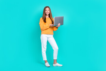 Full body size photo of cute excited teenager girl chatting online hold laptop remote education courses isolated on aquamarine color background