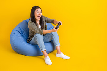 Full length photo of vietnamese girl wear casual outfit sit beanbag hold joystick addicted gamer...