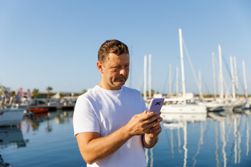 A man communicates on the phone against the background of yachts and a marina