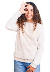 Beautiful kid girl with curly hair wearing casual clothes doing ok gesture with hand smiling, eye looking through fingers with happy face.