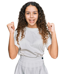 Teenager hispanic girl wearing casual white t shirt screaming proud, celebrating victory and success very excited with raised arms