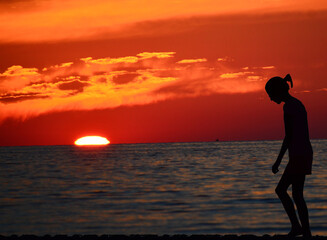 Fototapeta premium Erie silhouette of a person on the beach at sunset