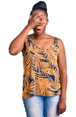 Young african american woman wearing casual clothes peeking in shock covering face and eyes with hand, looking through fingers with embarrassed expression.