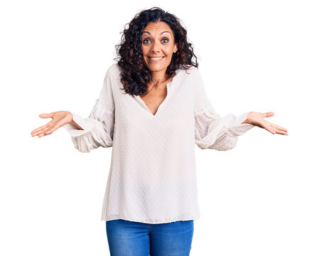 Middle age beautiful woman wearing casual sweater clueless and confused expression with arms and hands raised. doubt concept.