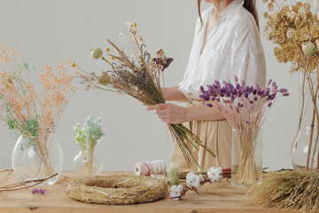 Medium height woman working with dried flowers assemble composition, decor and floristry concept