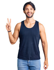 Handsome hispanic man wearing casual clothes smiling with happy face winking at the camera doing victory sign. number two.