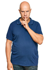 Middle age bald man wearing casual clothes asking to be quiet with finger on lips. silence and secret concept.