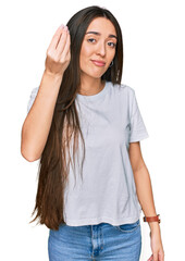 Young hispanic girl wearing casual white t shirt doing italian gesture with hand and fingers confident expression