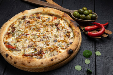 tasty pizza with cheese and vegetables on a wooden dark table
