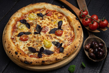 tasty pizza with cheese and vegetables on a wooden dark table
