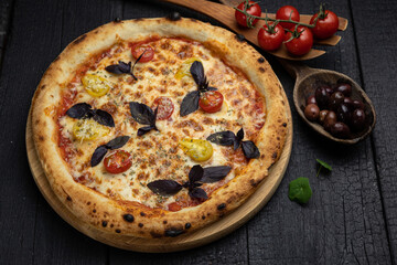 tasty pizza with cheese and vegetables on a wooden dark table
