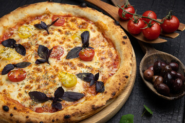 tasty pizza with cheese and vegetables on a wooden dark table
