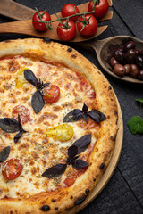 tasty pizza with cheese and vegetables on a wooden dark table
