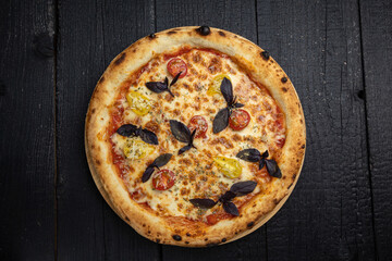tasty pizza with cheese and vegetables on a wooden dark table
