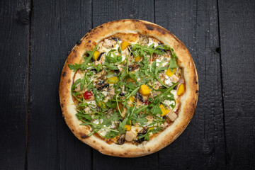 tasty pizza with cheese and vegetables on a wooden dark table
