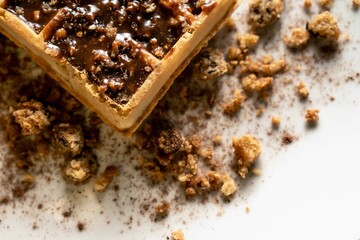 Closeup of a waffle with chocolate and cookie crumbs on a white plate in the kitchen