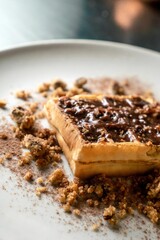 Vertical shot of a waffle with chocolate and cookie crumbs on a white plate in the kitchen