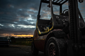 Old forklift after days work in sunset, cloudy weather