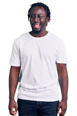Young african american man with braids wearing casual white tshirt winking looking at the camera with sexy expression, cheerful and happy face.
