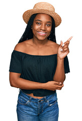 Young african american woman wearing summer hat smiling happy pointing with hand and finger to the side