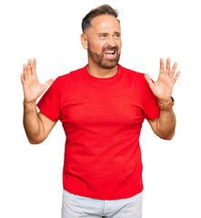 Handsome middle age man wearing casual red tshirt crazy and mad shouting and yelling with aggressive expression and arms raised. frustration concept.