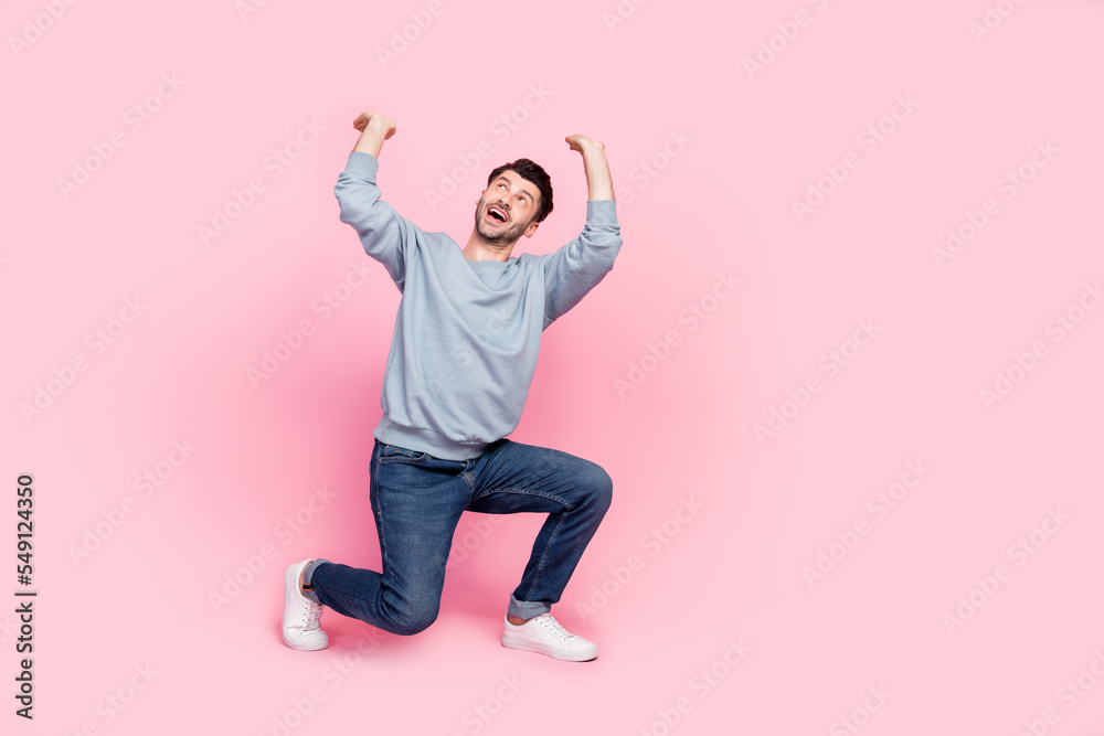 Wall mural full body photo of nice young guy raise hands carry invisible weight empty space dressed trendy blue