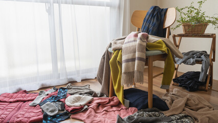 部屋中に散らばる服｜沢山の冬物の服