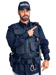 Young hispanic man wearing police uniform pointing aside worried and nervous with forefinger, concerned and surprised expression