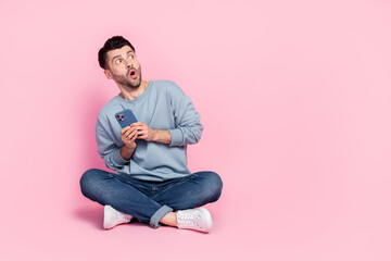 Full length photo of attractive young guy hold telephone terrified copyspace dressed trendy blue outfit isolated on pink color background